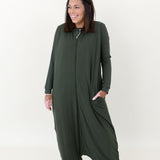 Model laughing while looking to the side and wearing the Adult Sleep Bag Walker in Fir with hand in pocket