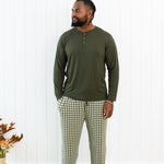 Model standing in front of a white paneled wall in the Men's Lounge Pants in Gingham Fir and Fir Henley 