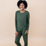 Model in a tan room wearing the Smiling model in grassy field wearing the Kyte Women's Jogger Set in Fir