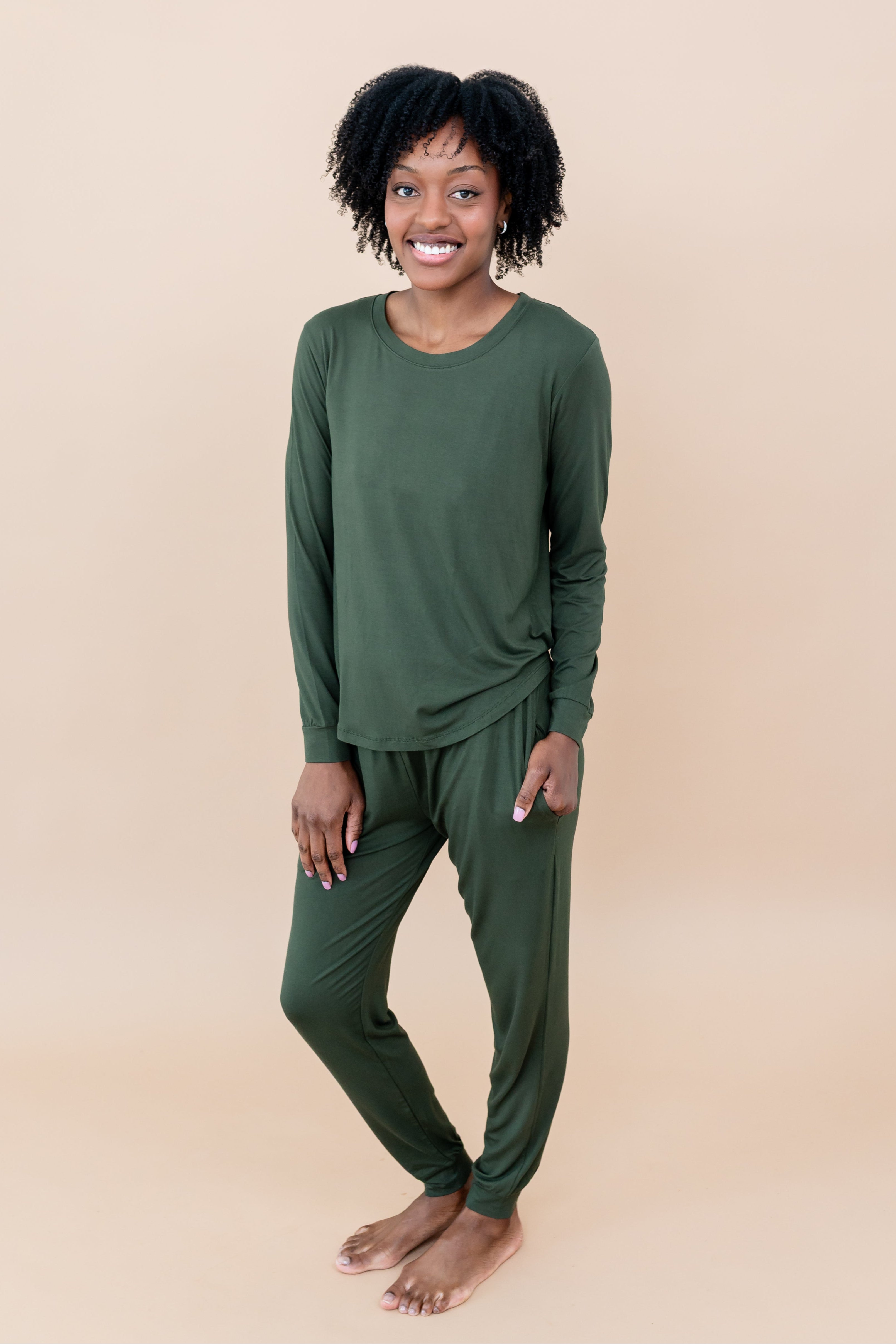 Model in a tan room wearing the Smiling model in grassy field wearing the Kyte Women's Jogger Set in Fir
