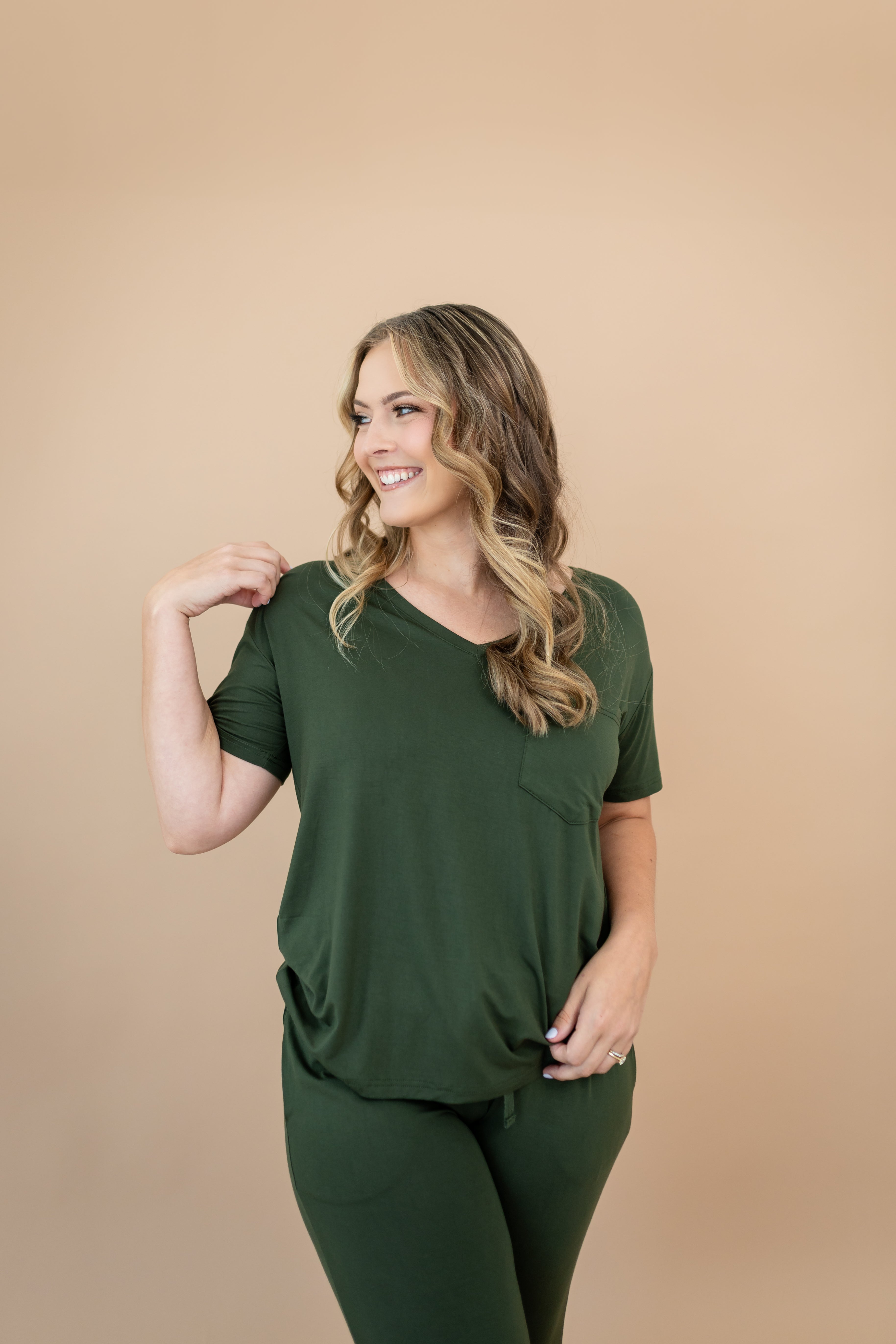 Smiling woman looking to the side while modeling the Women's V Neck in Fir and matching lounge pants
