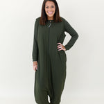 Smiling model wearing the Kyte Adult Sleep Bag Walker in Fir with hand on hip and matching top beneath it