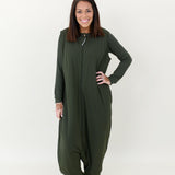 Smiling model wearing the Kyte Adult Sleep Bag Walker in Fir with hand on hip and matching top beneath it