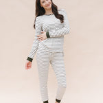 Model with one arm across body while wearing the Kyte Women’s Ribbed Henley Set in Fir Stripe