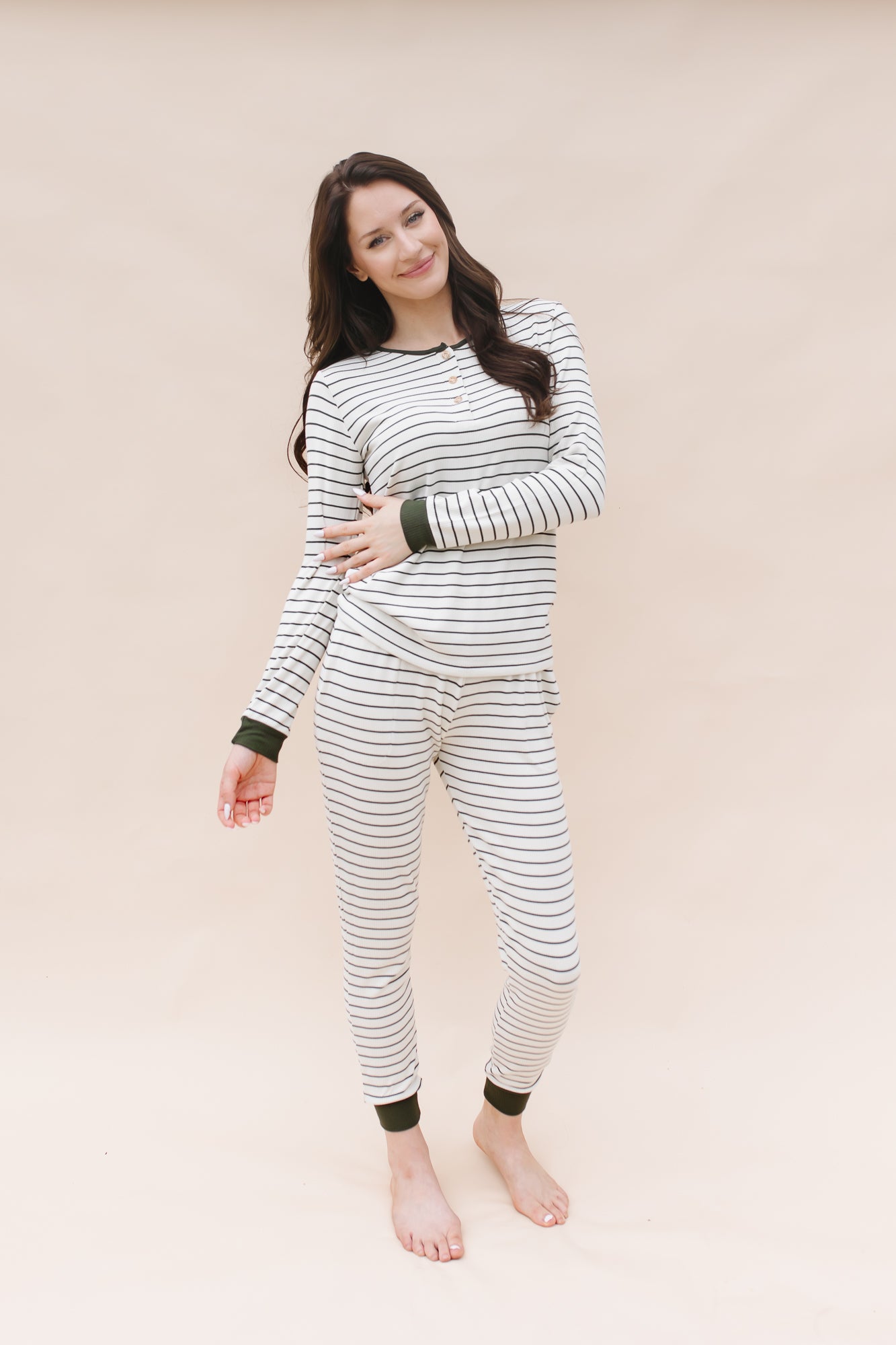 Model with one arm across body while wearing the Kyte Women’s Ribbed Henley Set in Fir Stripe