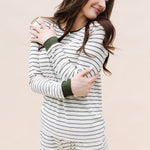 Model looking to the side while hugging herself while wearing the Kyte Women’s Ribbed Henley Set in Fir Stripe