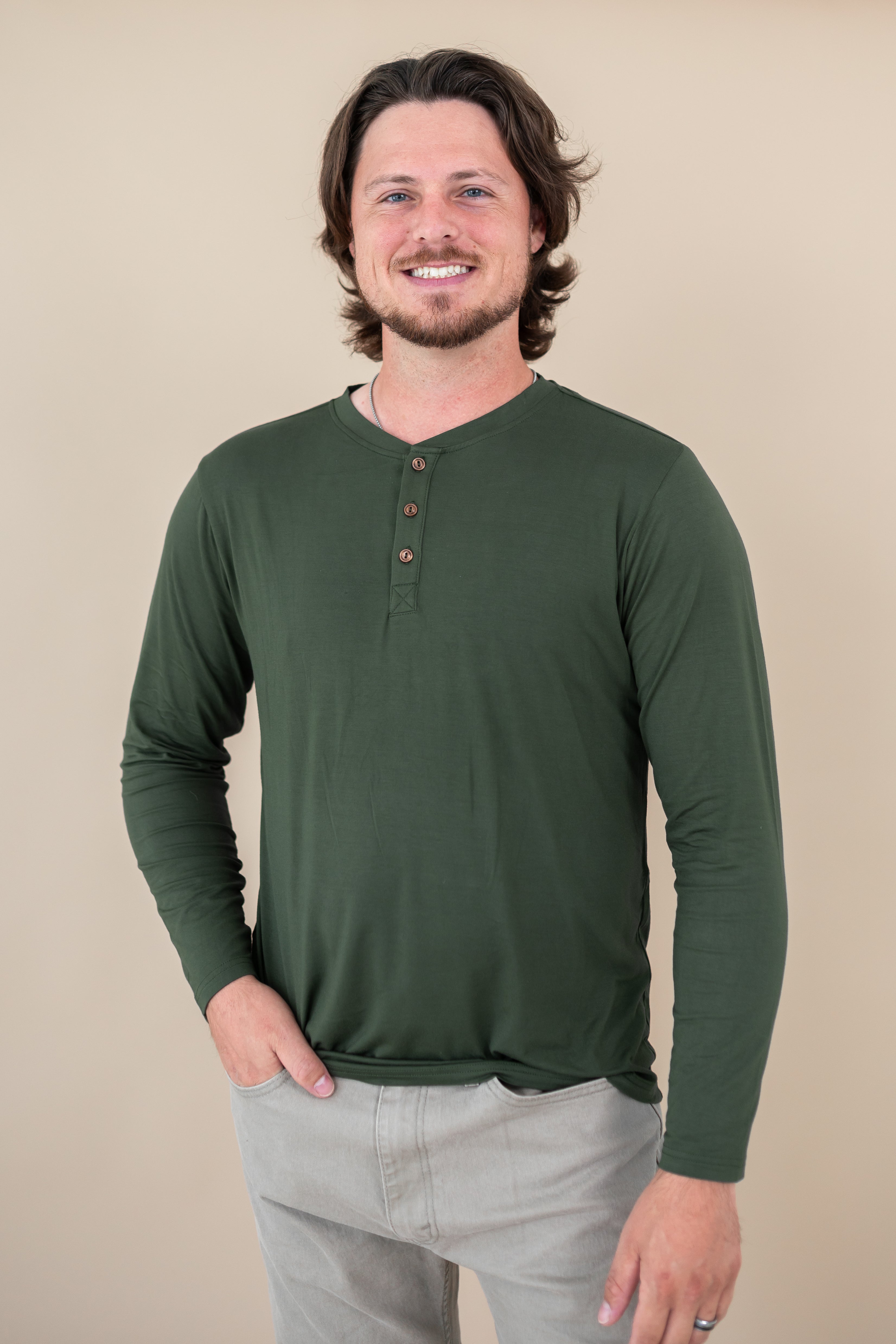 Smiling male model wearing the Kyte Men's Long Sleeve Henley Top in Fir