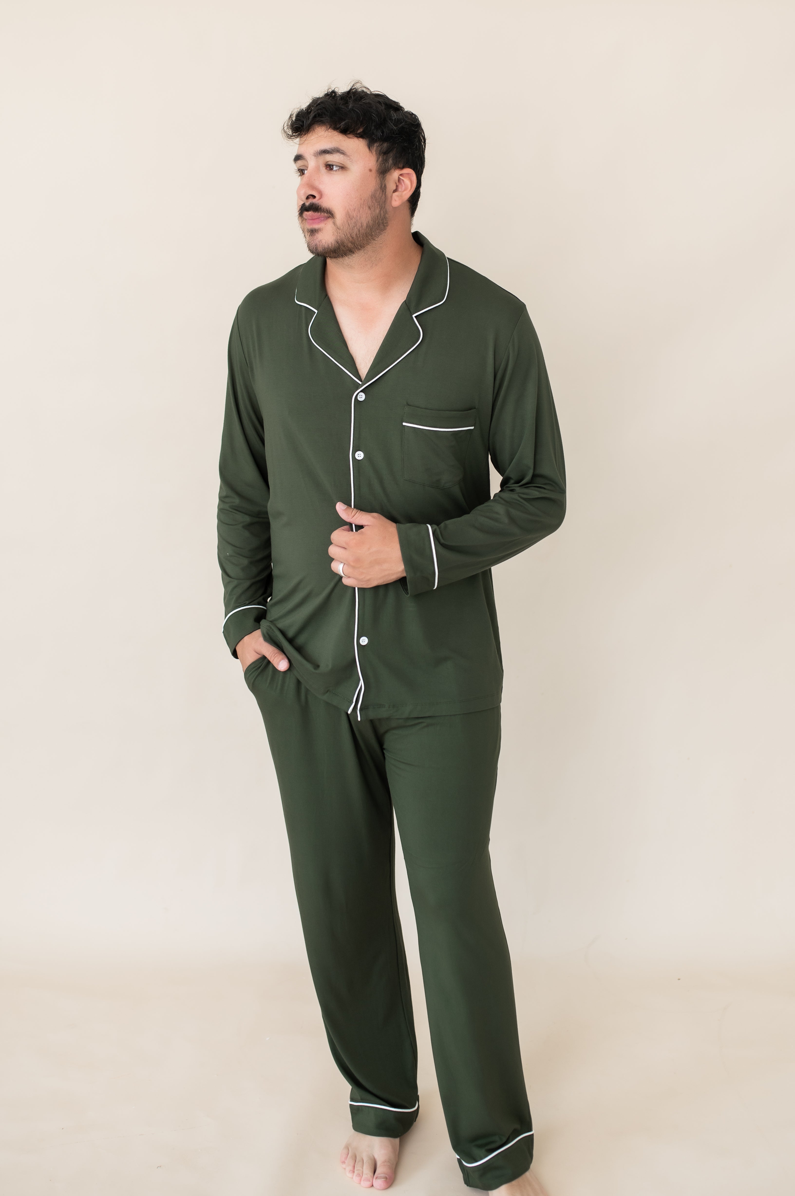 Model standing with one hand on stomach and one in pocket while wearing the Kyte Men's Long Sleeve Pajama Set in Fir