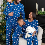 Family of 4 and dog all wearing matching holiday pajamas that are blue with a winter forest animal print
