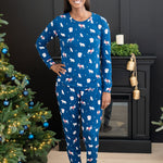 Smiling female model standing with one hand on her hip wearing the Women's Jogger Pajama Set in Frosty Friends in front of a black fireplace and between two decorated Christmas trees