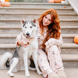 Female model sitting at the bottom of concrete steps wearing the Long-Sleeved Women's Pajama Set in Gilmore Girls with her arm around a husky 