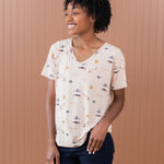 Smiling model looking to the side and wearing the Women's Relaxed Fit V-Neck in Gilmore Girls paired with dark jeans