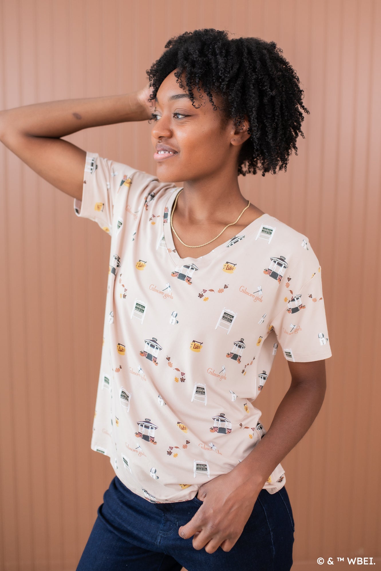 Model looking to the side with one hand in hair while modeling the Kyte Women's Relaxed Fit V-Neck in Gilmore Girls