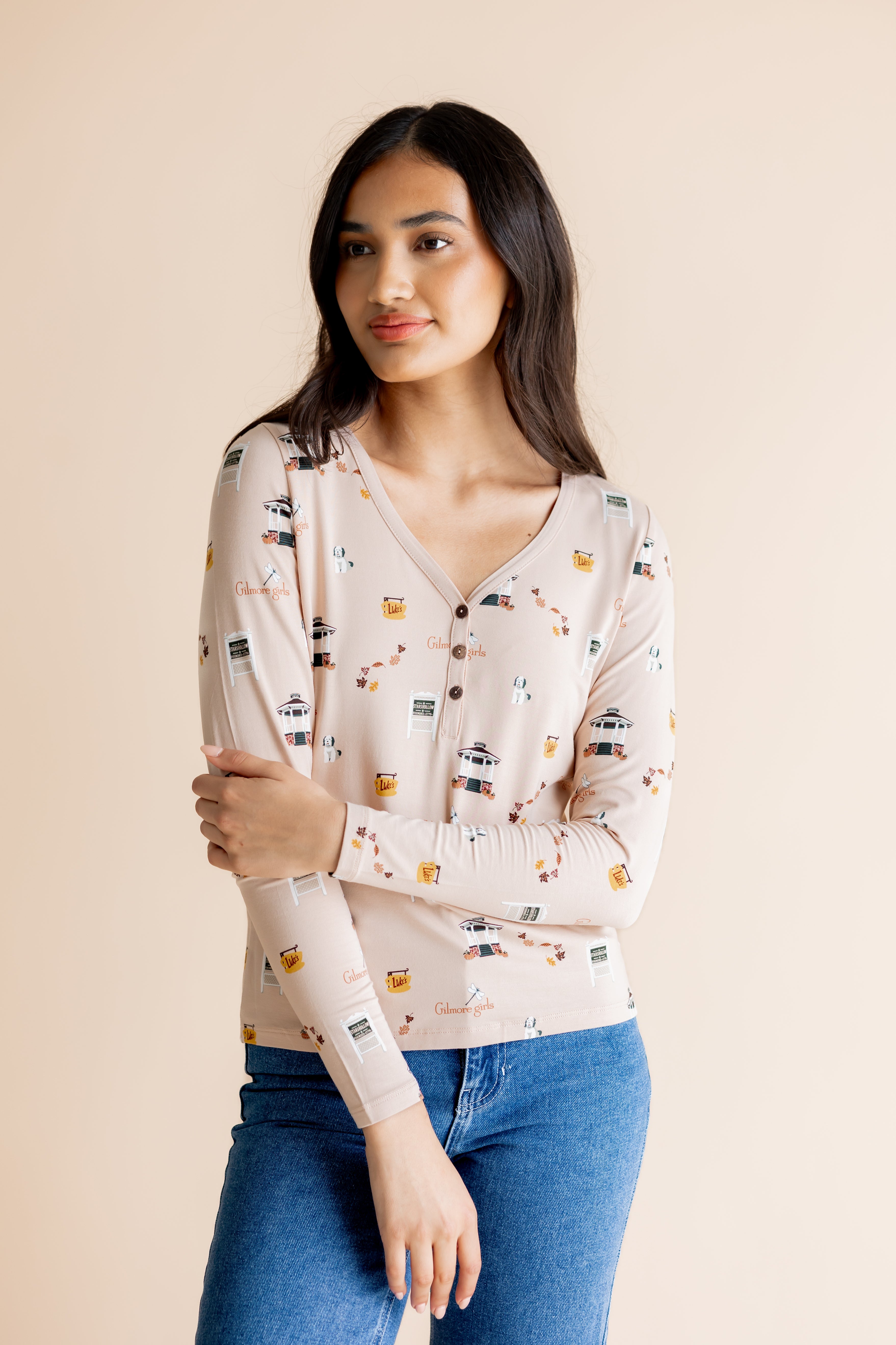 Woman with arms crossed in front of her body while modeling the Women's Long Sleeve Henley Tee in Gilmore Girls paired with jeans