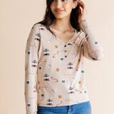 Model looking to the side in front of a beige background while wearing the Women's Long Sleeve Henley Tee in Gilmore Girls paired with medium wash denim jeans