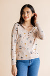 Model looking to the side in front of a beige background while wearing the Women's Long Sleeve Henley Tee in Gilmore Girls paired with medium wash denim jeans