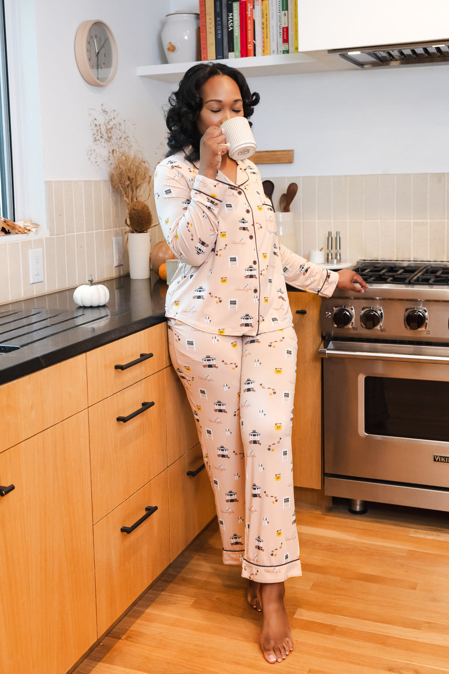 Woman drinking from a mug in a kitchen while wearing the Long-Sleeved Women's Pajama Set in Gilmore Girls