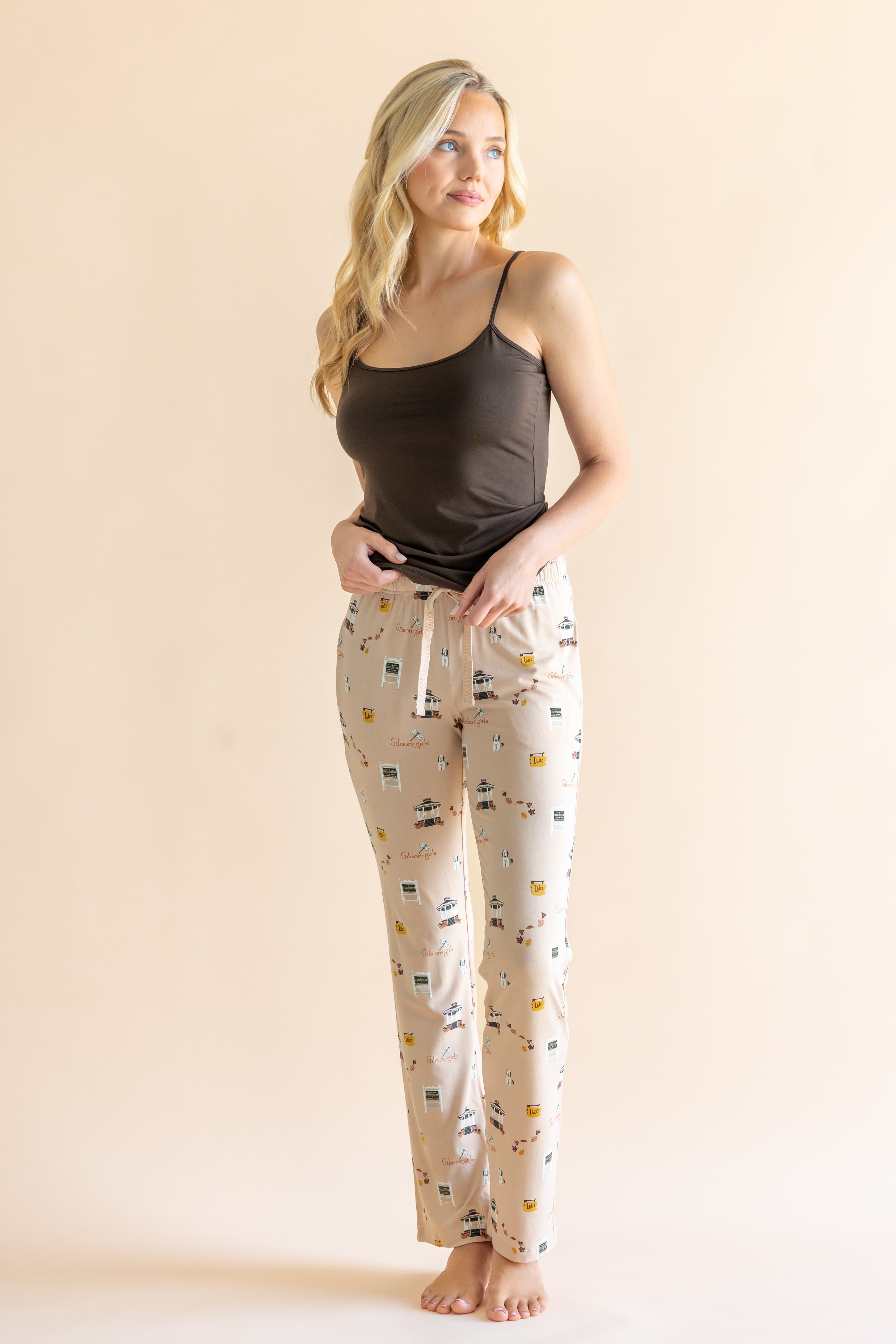 Model standing in front of a beige background wearing the Women's Lounge Pants in Gilmore  Girls paired with a coffee cami ::: Model is 5'9" wearing size XS ///