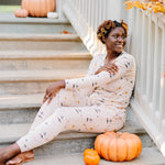 Woman sitting on concrete stairs next to a pumpkin while modeling the Women's Jogger Pajama Set in Gilmore Girls