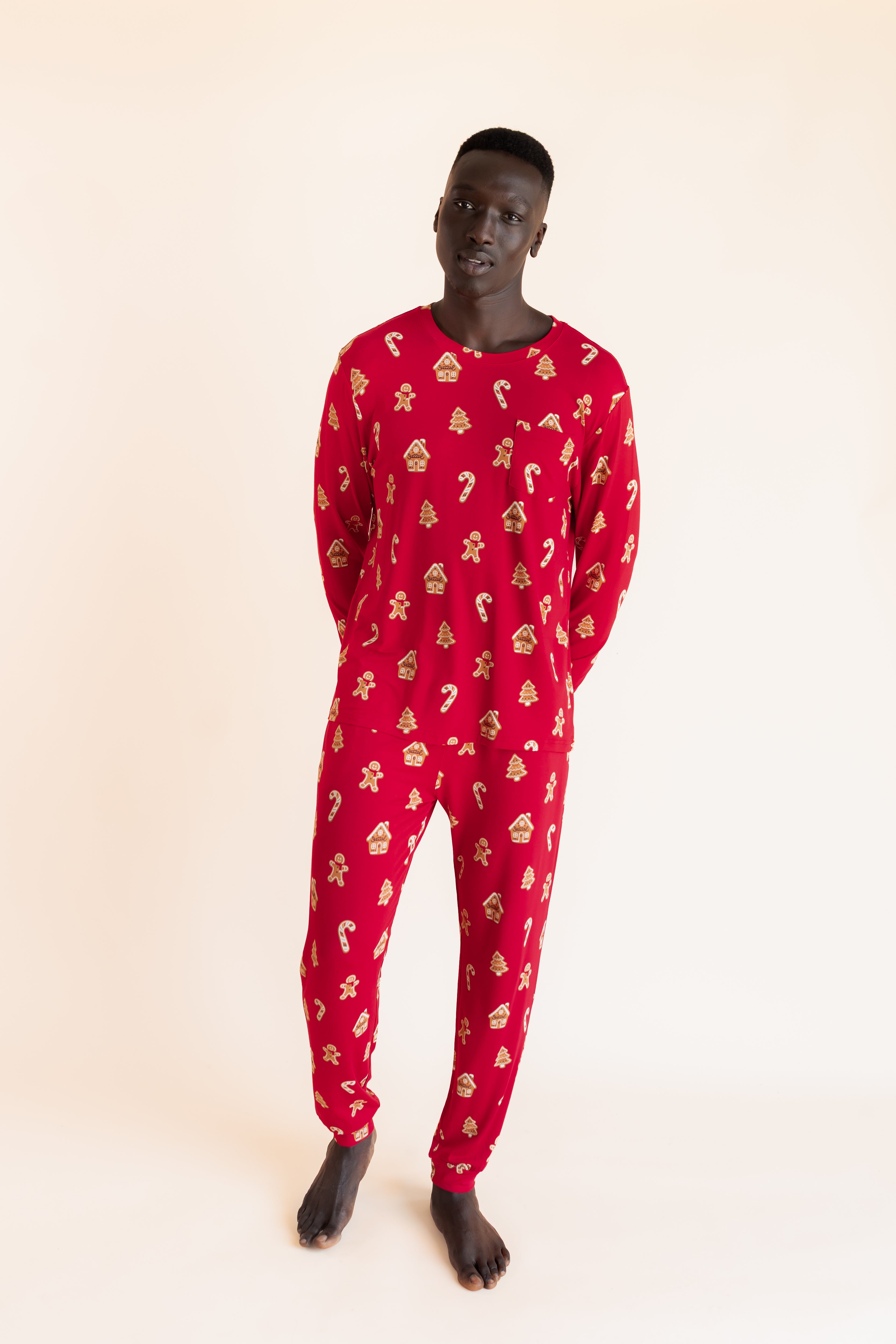 Man with his hands behind his back wearing a jogger set in gingerbread print.
