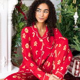 Woman sitting with one leg bent in with the other propped up looking over to the side in long sleeve pajama set in gingerbread print

---PJ 
