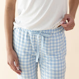 Person wearing a white t-shirt and light blue gingham pajama pants on a beige background