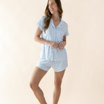 Woman wearing a blue checkered pajama set on a beige background