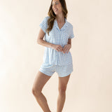 Woman wearing a blue checkered pajama set on a beige background