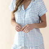 Woman wearing a blue and white checkered romper on a beige background
