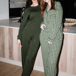  Models standing next to a counter while wearing the Women's Long Sleeve Pajama Set in Gingham Fir and Jogger Set in Fir