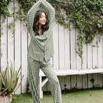 Model standing infront of white fence and Women's Long Sleeve Pajama Set in Gingham Fir