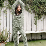 Model standing infront of white fence and Women's Long Sleeve Pajama Set in Gingham Fir