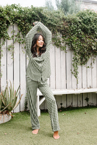 Model standing infront of white fence and Women's Long Sleeve Pajama Set in Gingham Fir