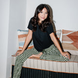 Woman sitting in a book nook while modeling the Women's Lounge Pants in Gingham Fir
