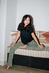 Woman sitting in a book nook while modeling the Women's Lounge Pants in Gingham Fir
