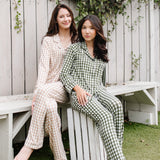 Models sitting on a bench wearing  the Women's Long Sleeve Pajama Set in Gingham Fir and Gingham Bisque