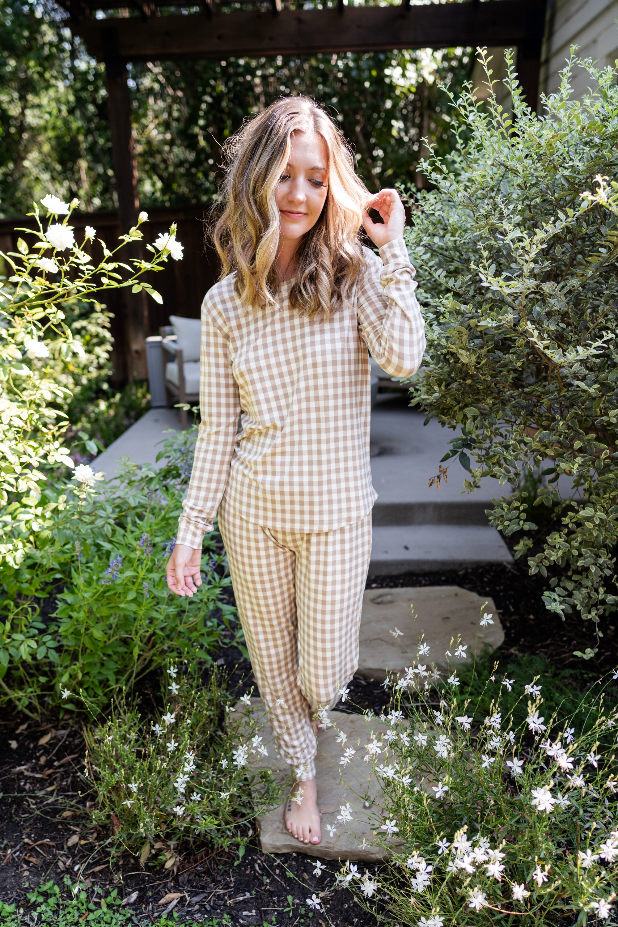 Model standing in greenery while wearing the Women's Jogger Set in Gingham Bisque