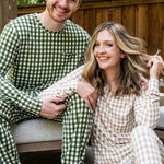 Male model sitting on a bench wearing the Jogger Set in Gingham Fir while woman sits on floor wearing the Jogger Set in Gingham Bisque