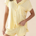 Woman wearing a yellow checkered pajama set against a beige background