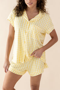 Woman wearing a yellow checkered pajama set against a beige background