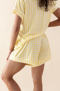 Person wearing a yellow checkered dress against a beige background