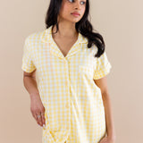Woman wearing a yellow checkered pajamas against a beige background