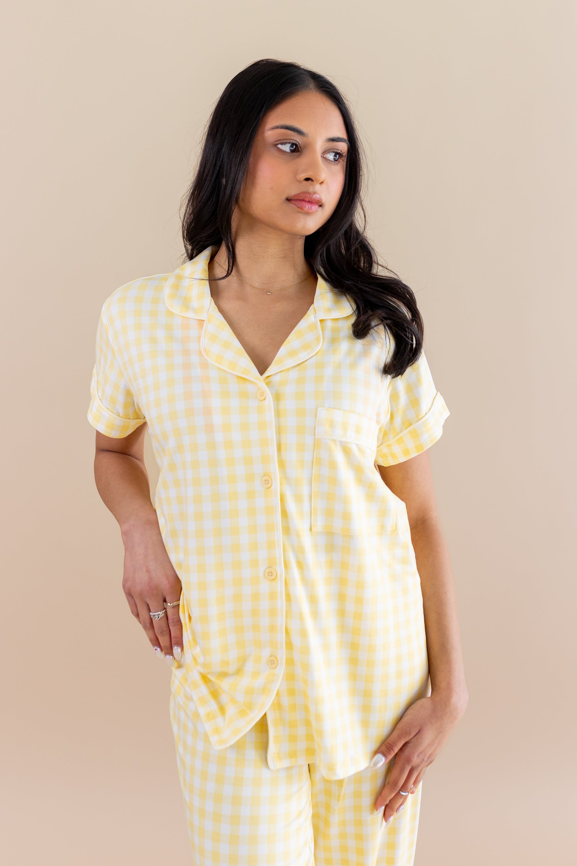 Woman wearing a yellow checkered pajamas against a beige background