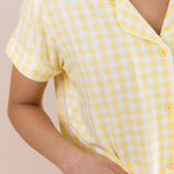 Yellow checkered pajama shirt worn by a person on a beige background