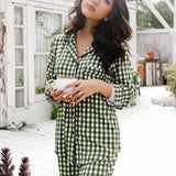 Woman wearing a green and white checkered outfit standing outdoors holding coffee cup