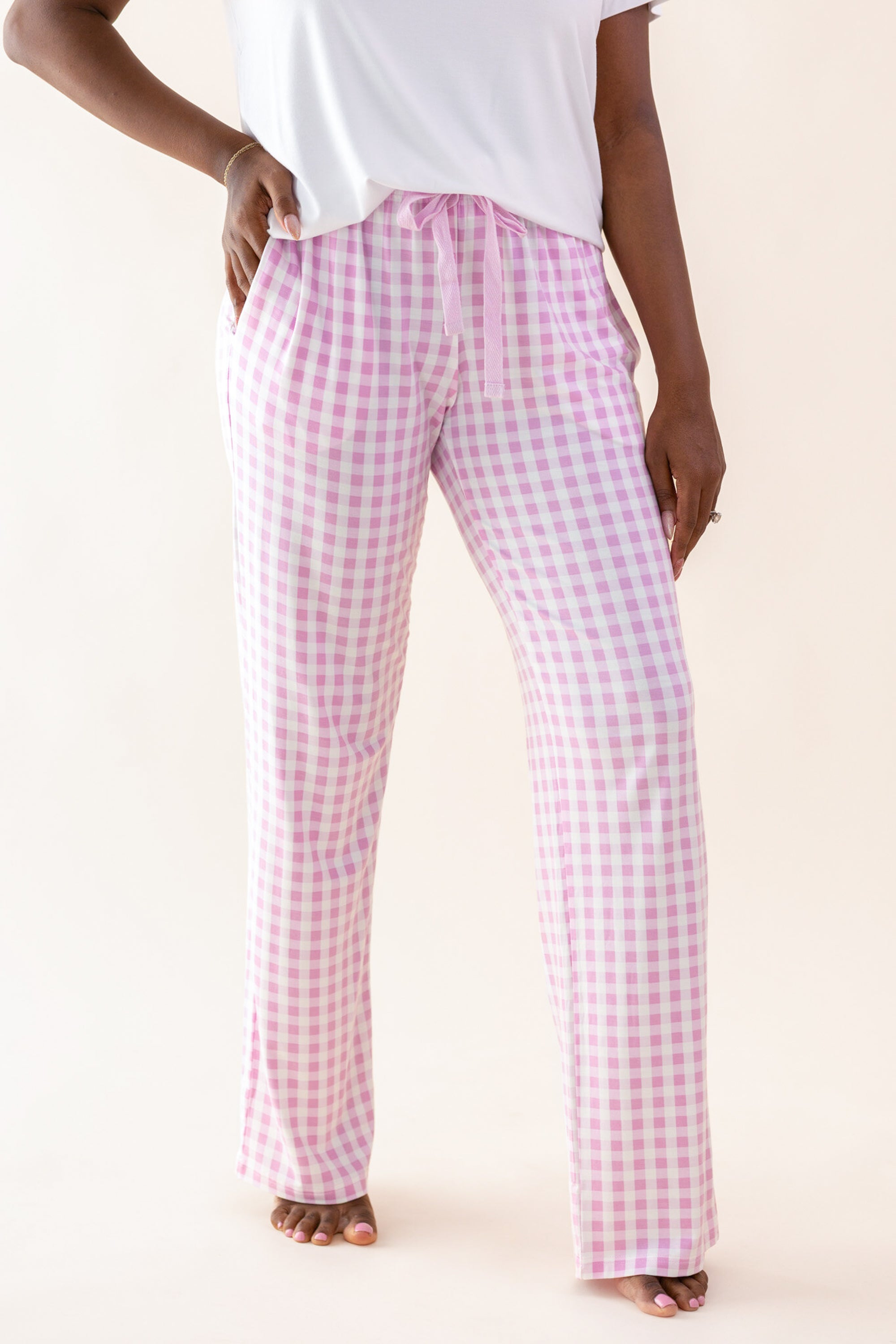 Person wearing pink gingham pants on a white background