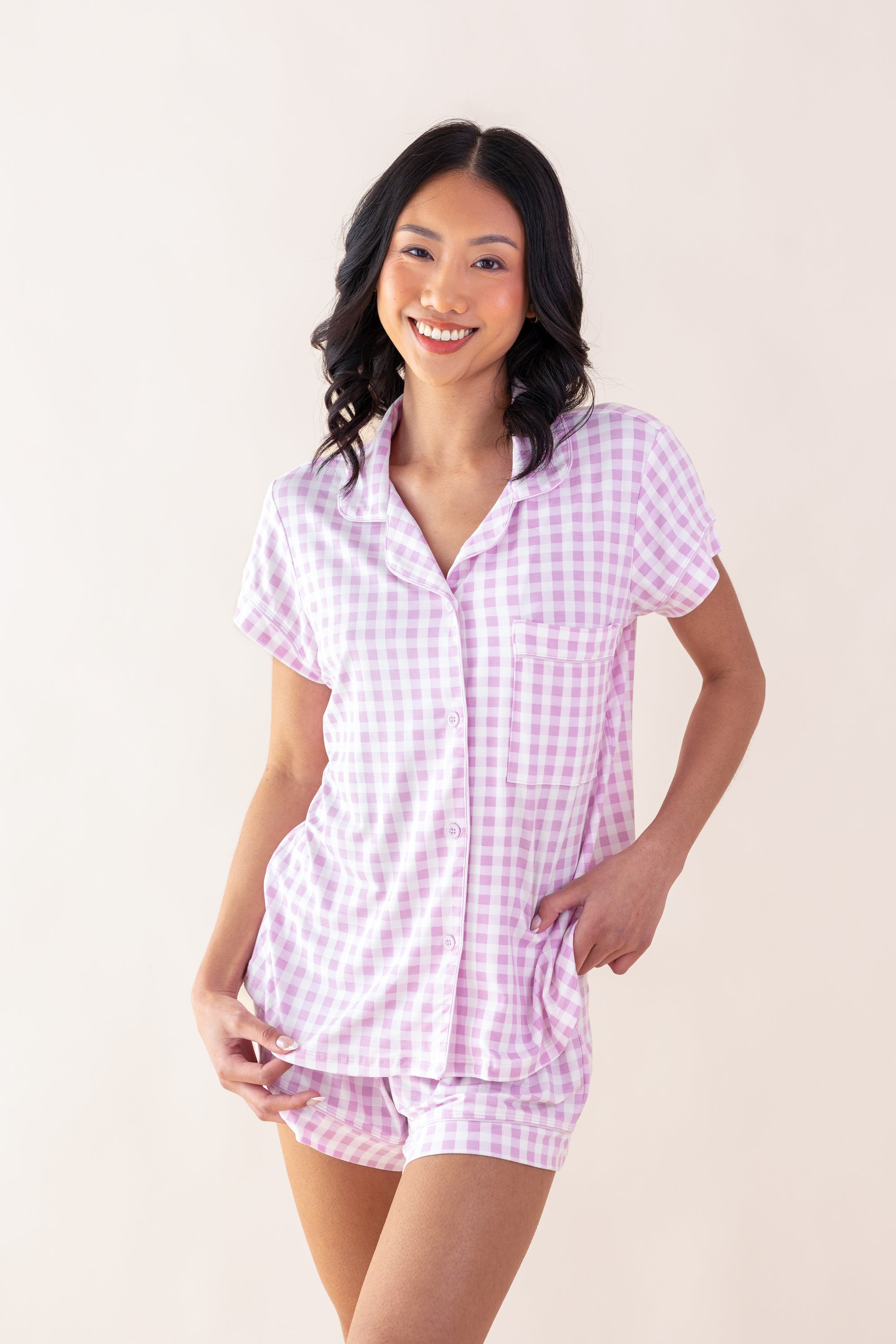 Woman wearing a pink and white checkered pajama set against a plain background
