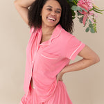 Woman modeling Women’s Short Sleeve Pajama Set in Guava with Cloud Trim holding a bouquet above head