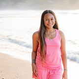 Female model on the beach wearing the Women’s Tank Set in Guava