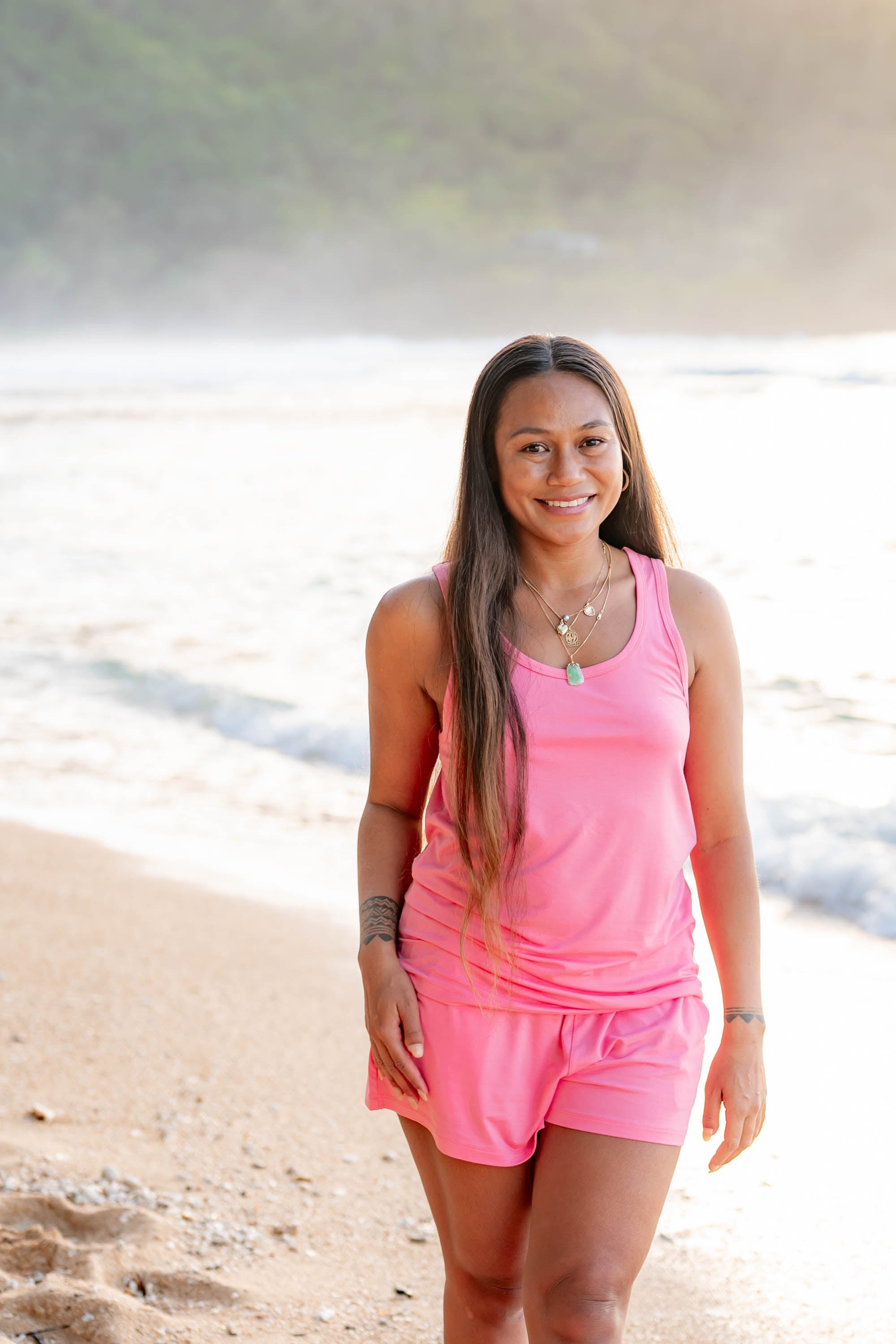 Female model on the beach wearing the Women’s Tank Set in Guava